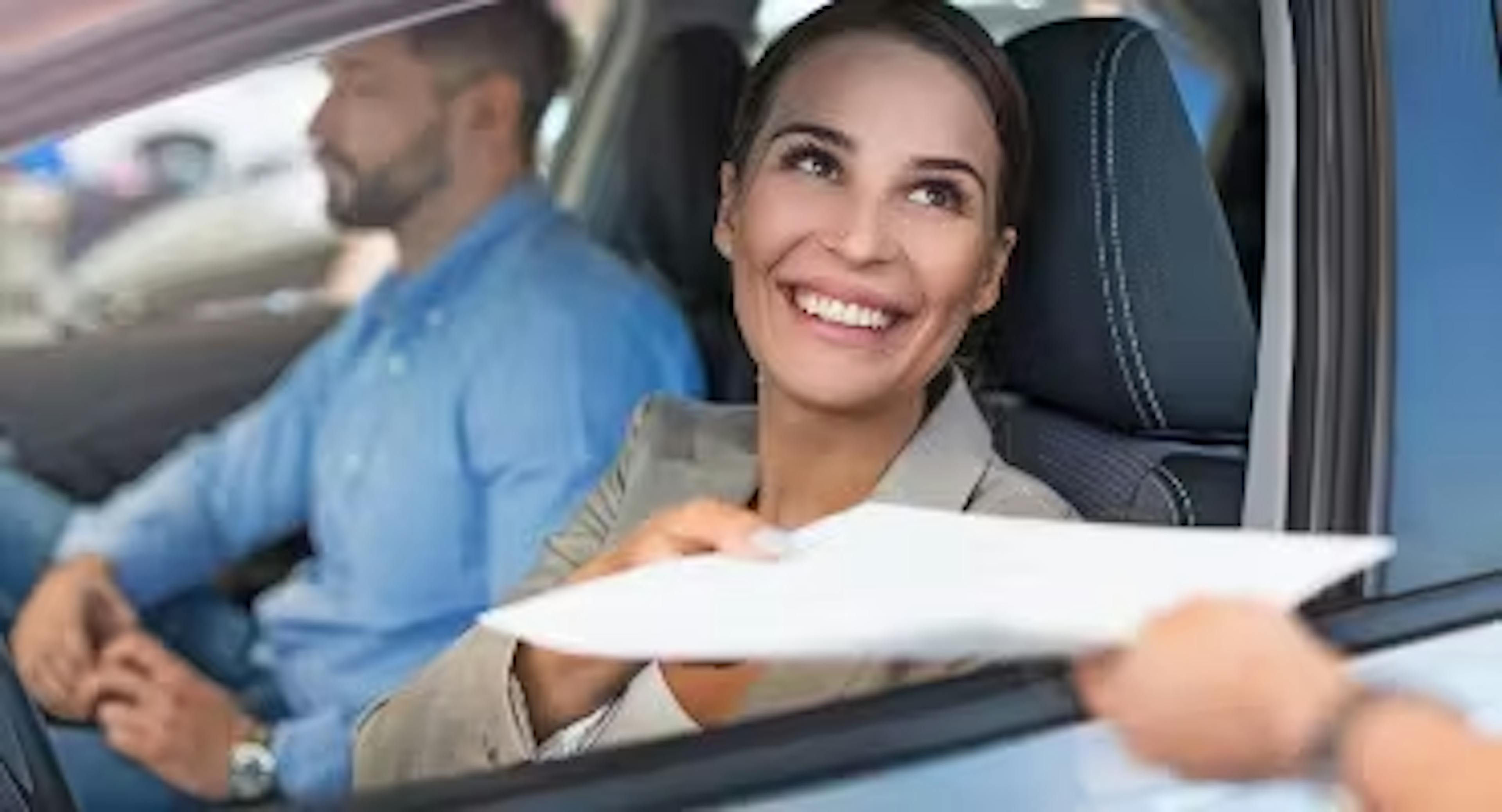 Femme examinant des documents d'assurance dans une voiture