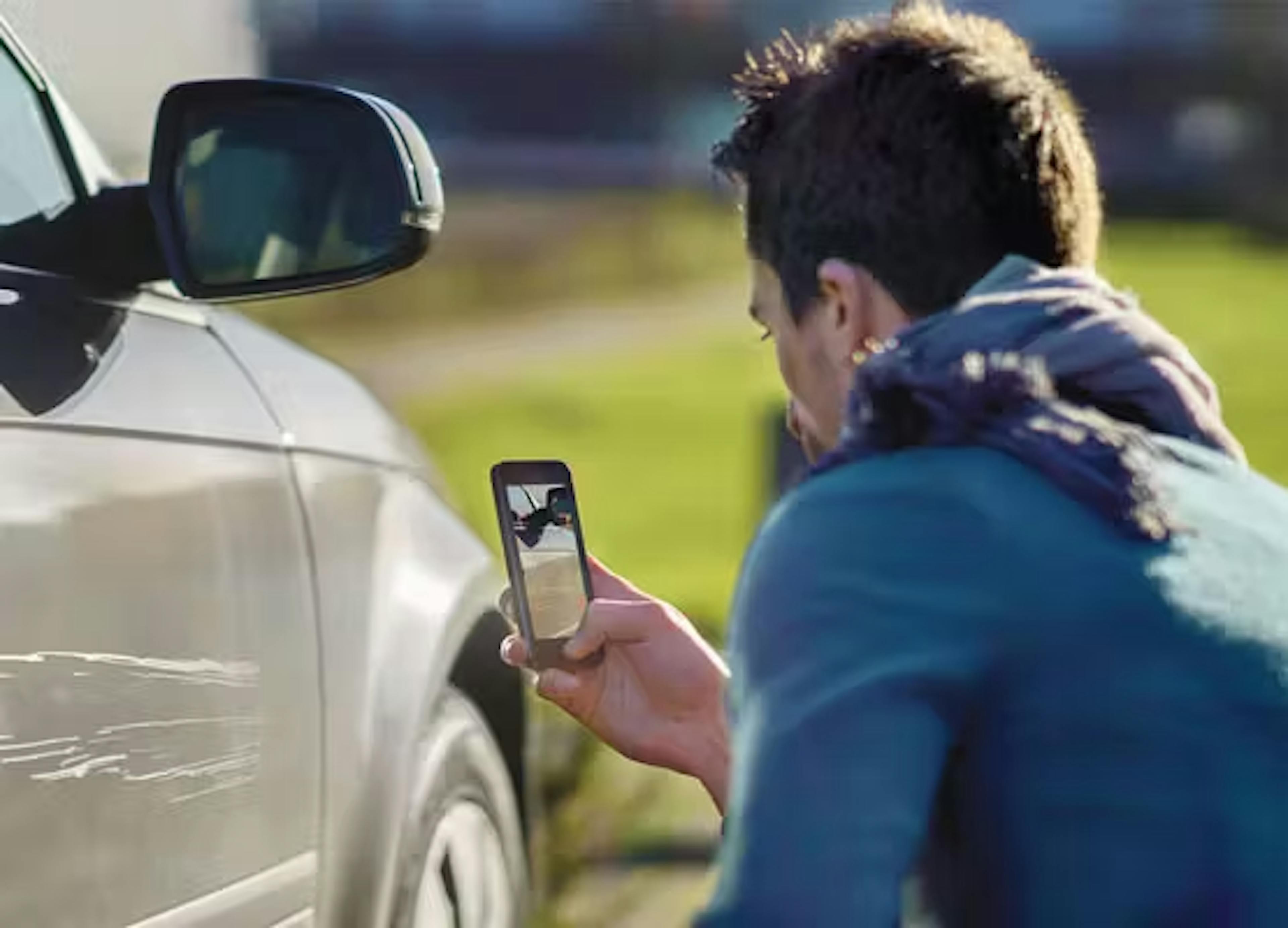 Persoon fotografeert autoschade met smartphone