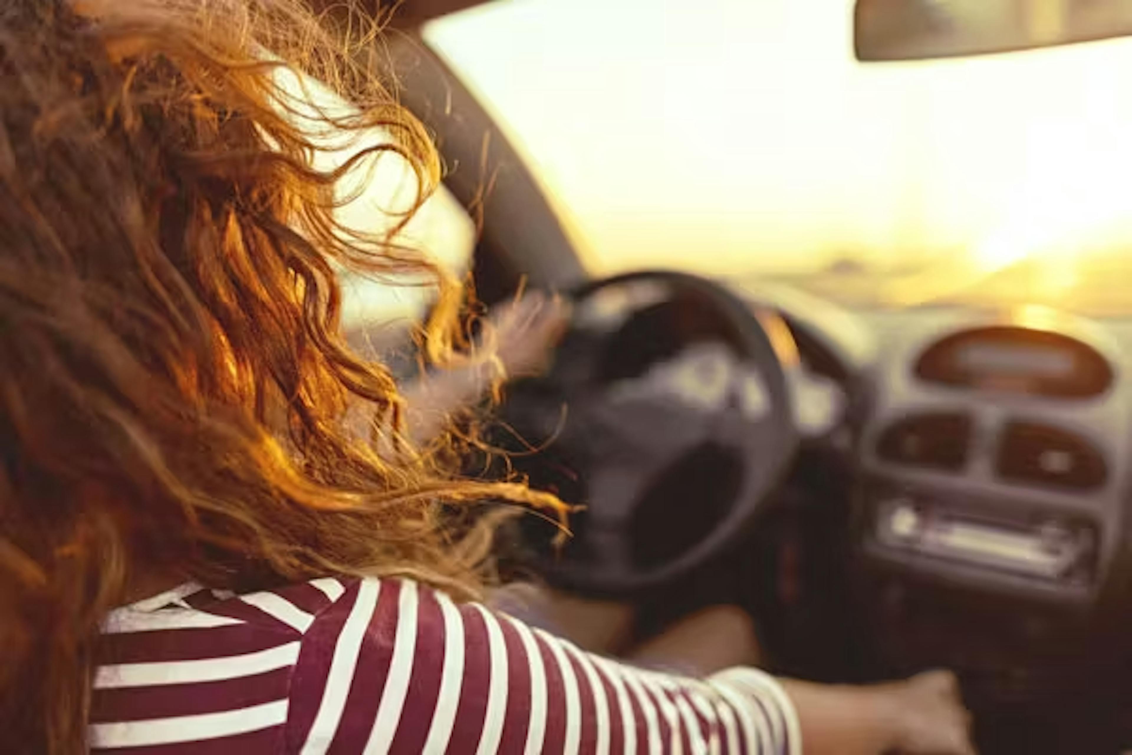 Femme conduisant une voiture au coucher du soleil